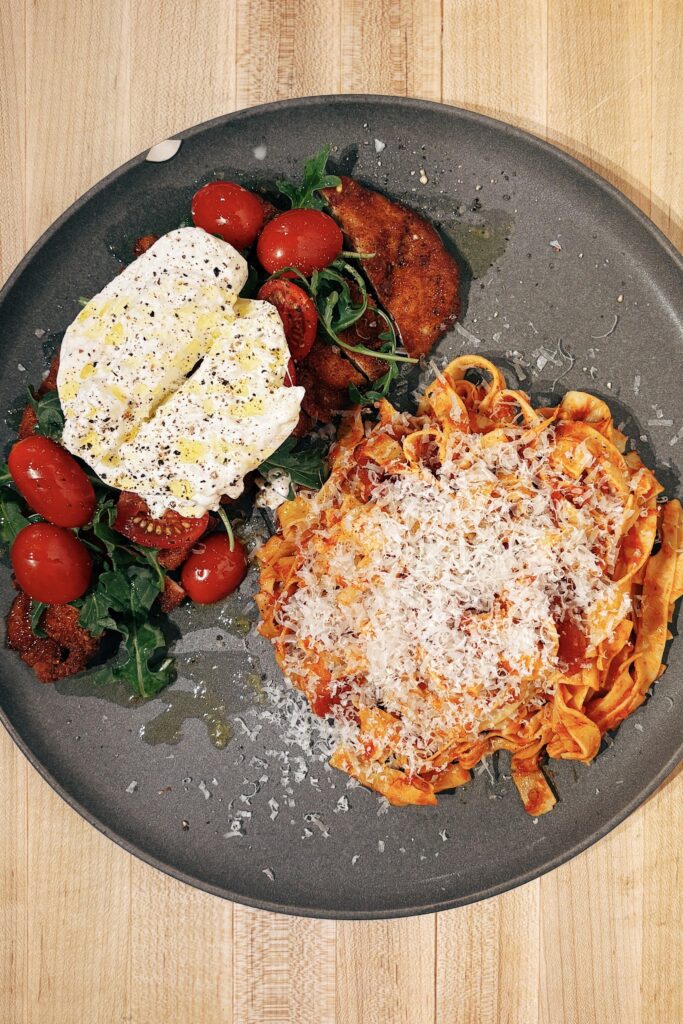 皿に盛られたパスタとカツレツとサラダ