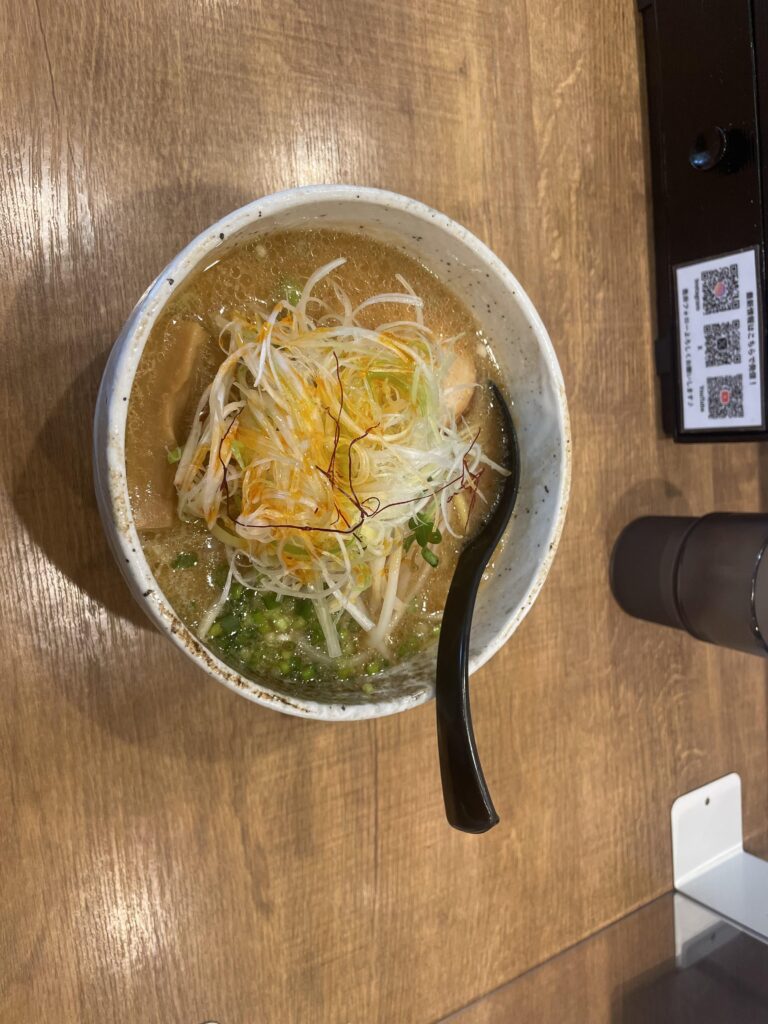 木目調の机に置かれたネギたっぷりラーメン