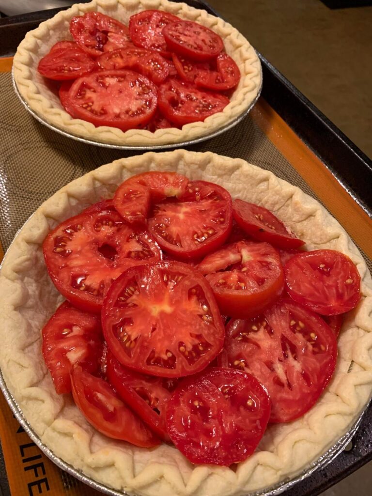 トマトを敷き詰めた焼く前の二つのパイ