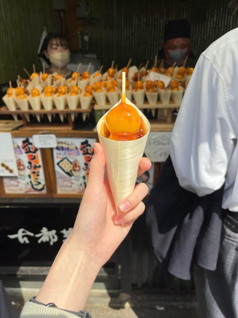 屋台で買った串団子を手に持つ様子