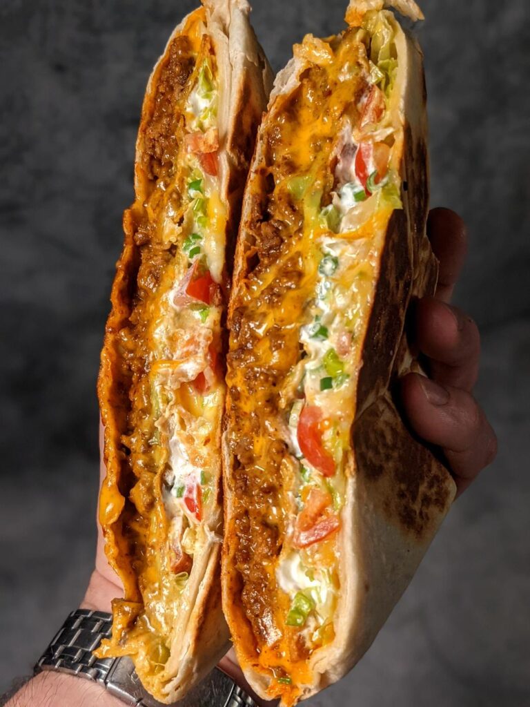 具沢山のブリトーの断面を持つ人の手