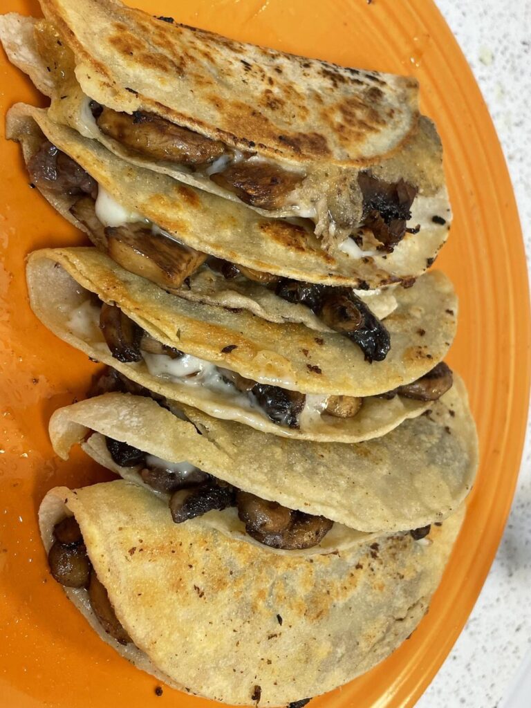 オレンジの皿に並ぶきのこのケサディーヤ