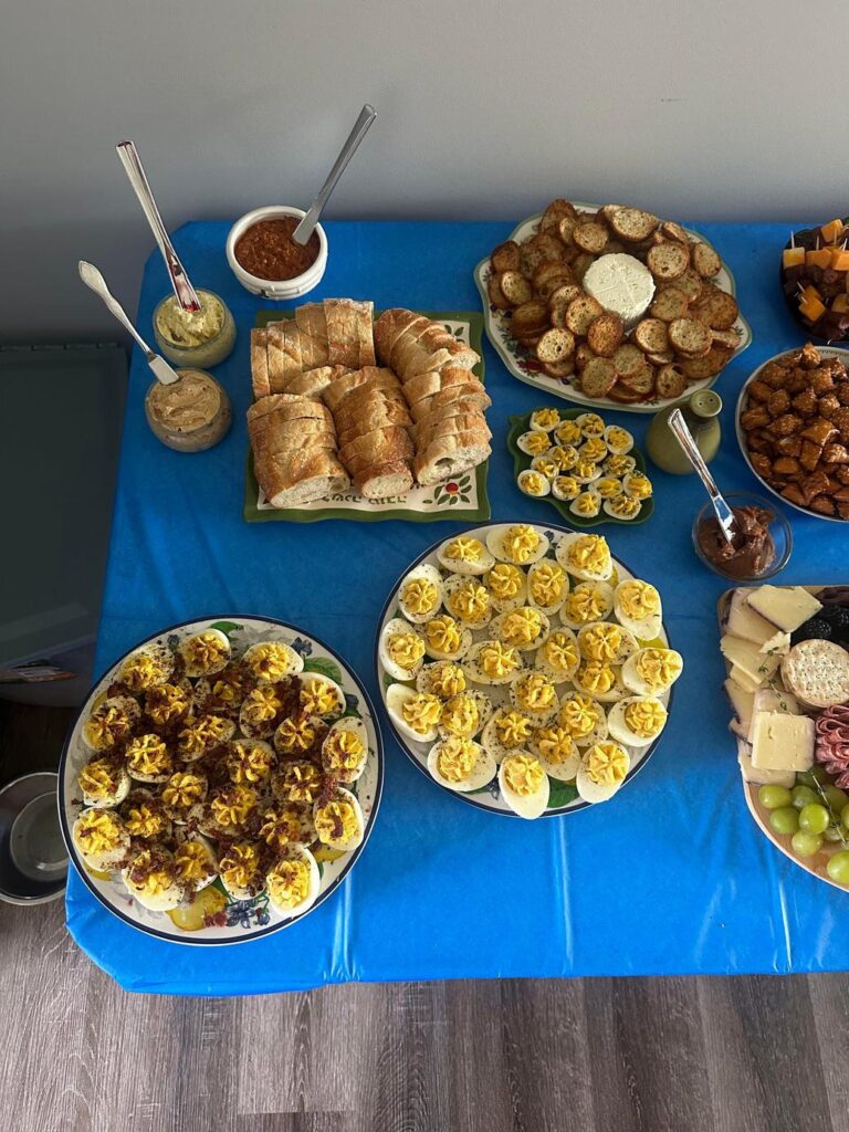 青いテーブルに並ぶ卵料理やパンなどの軽食