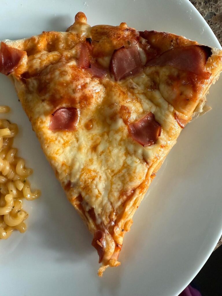 白い皿に乗ったハムのピザとパスタ